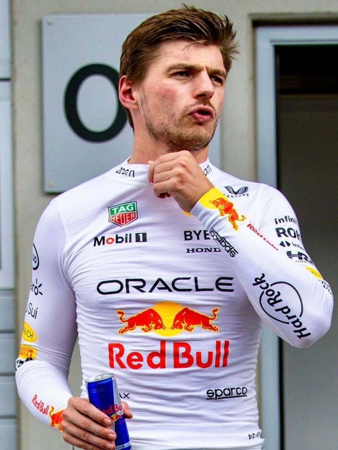 Person wearing a white racing suit with Red Bull and Oracle logos.