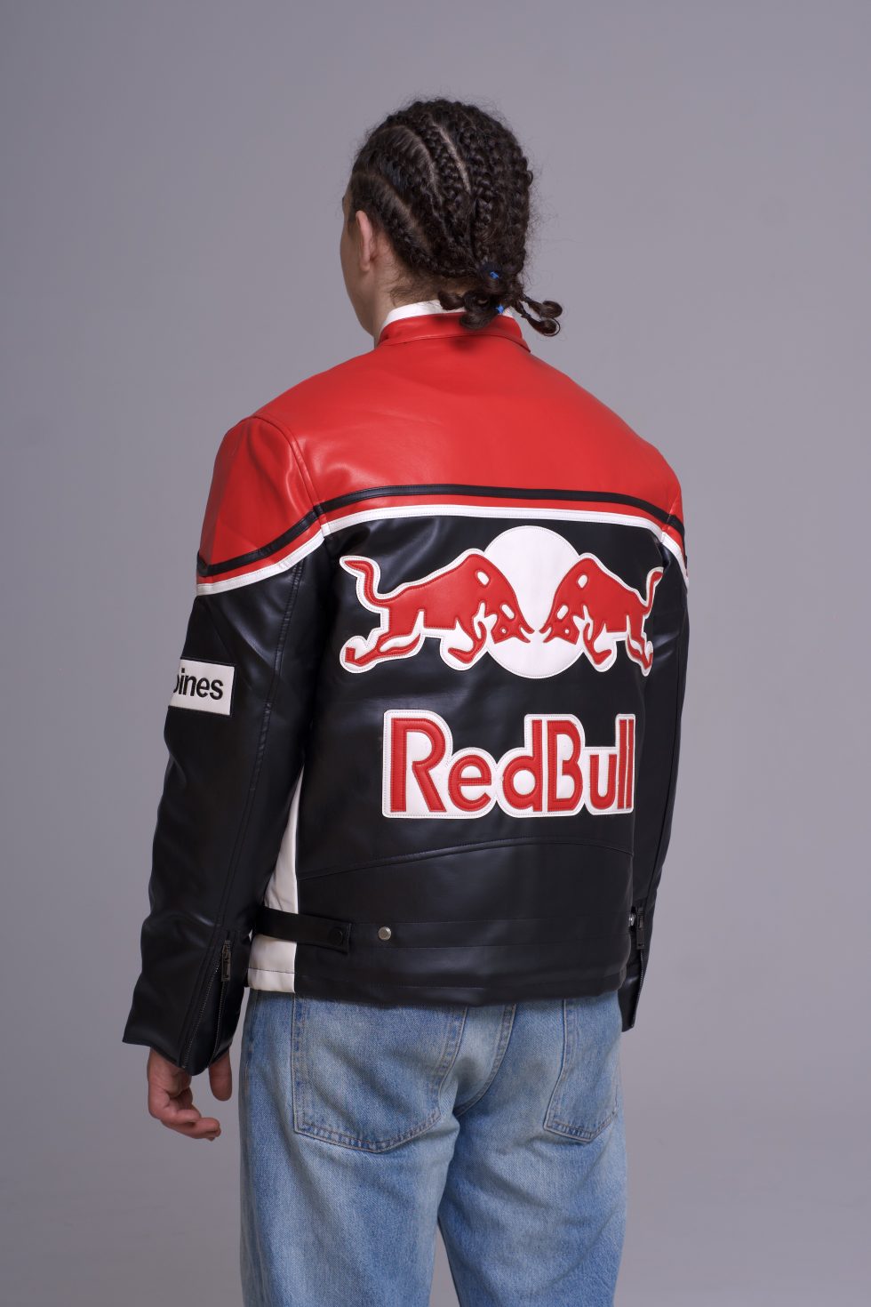 Person wearing a red and black leather jacket with Red Bull logo on a gray background