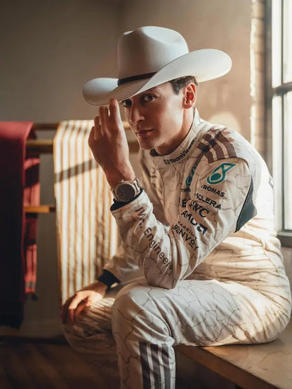 Person wearing a white racing suit with sponsor logos and a cowboy hat indoors.