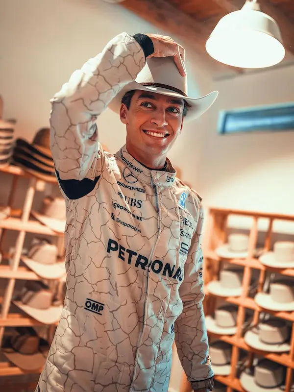 Person wearing a racing suit with petronas branding in a room with shelves of hats.