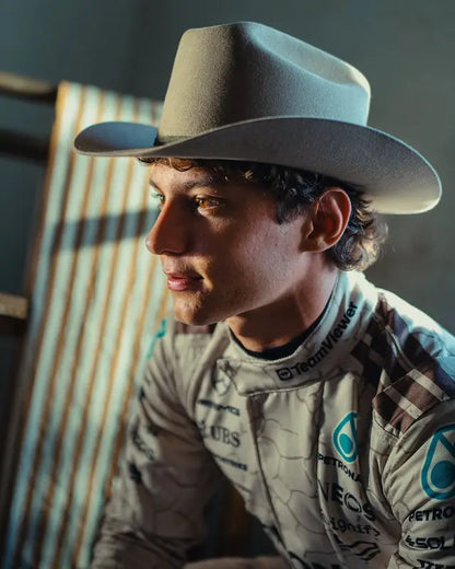 Person wearing a cowboy hat and racing suit with sponsor logos.