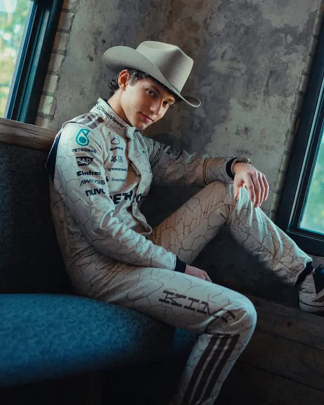 Person wearing a racing suit and cowboy hat sitting in a vehicle.