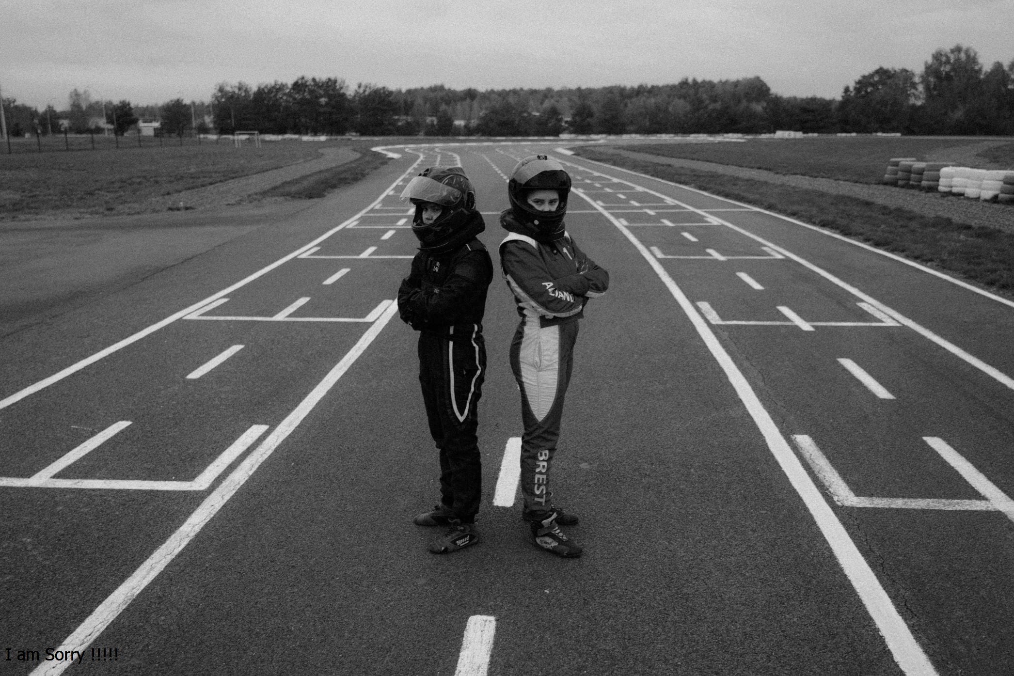 Two people standing on a race track in black and white.